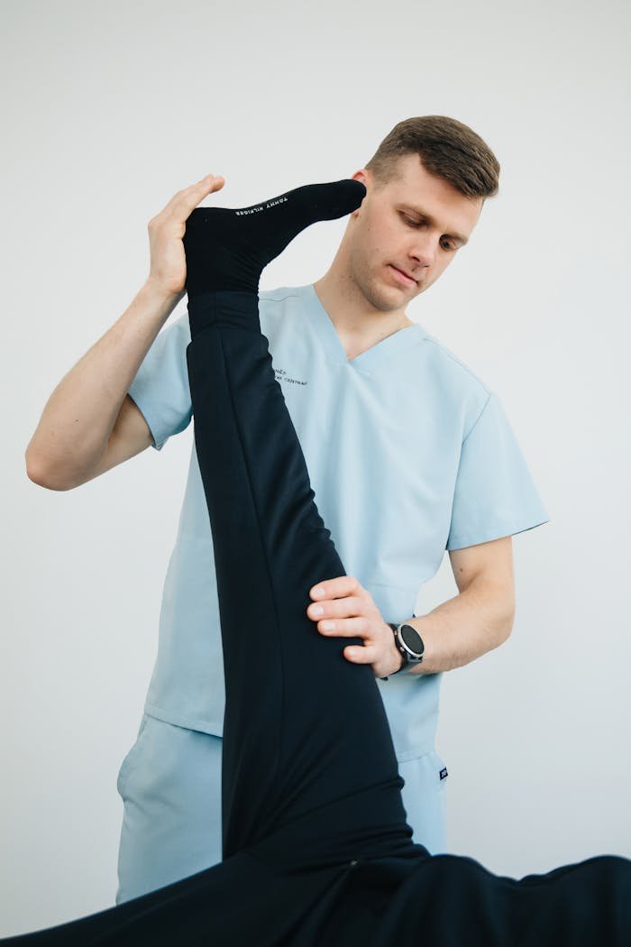 Home Professional physiotherapist helping a patient with leg exercises in a clinic setting.